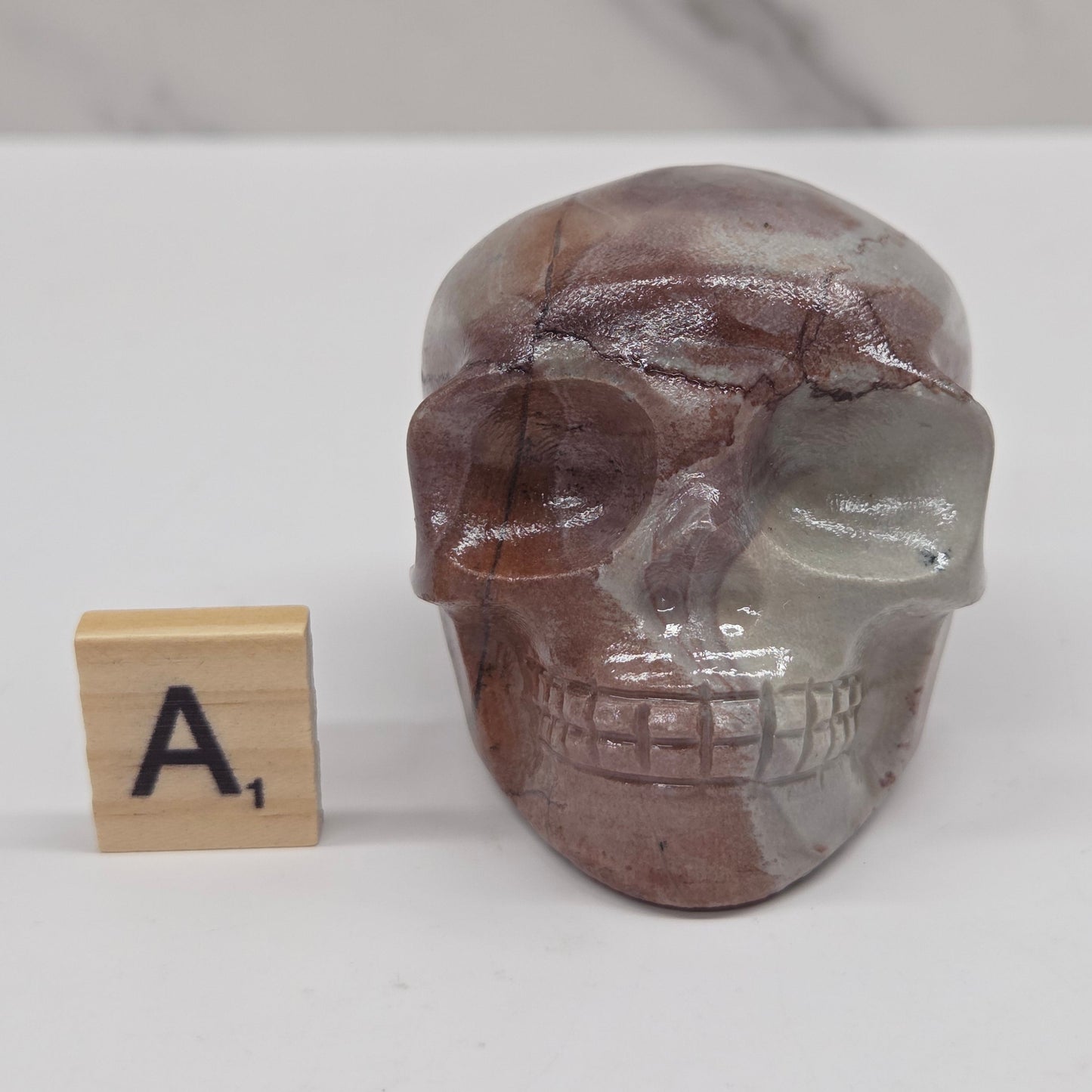 skull carving with pink and grey coloring on a white background
