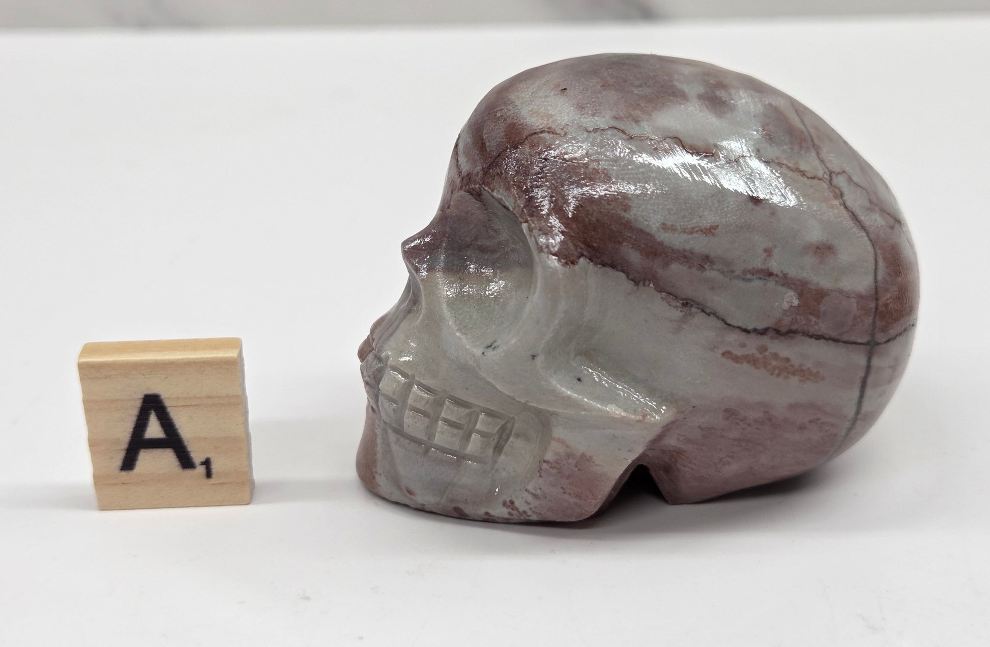 skull carving with pink and grey coloring on a white background