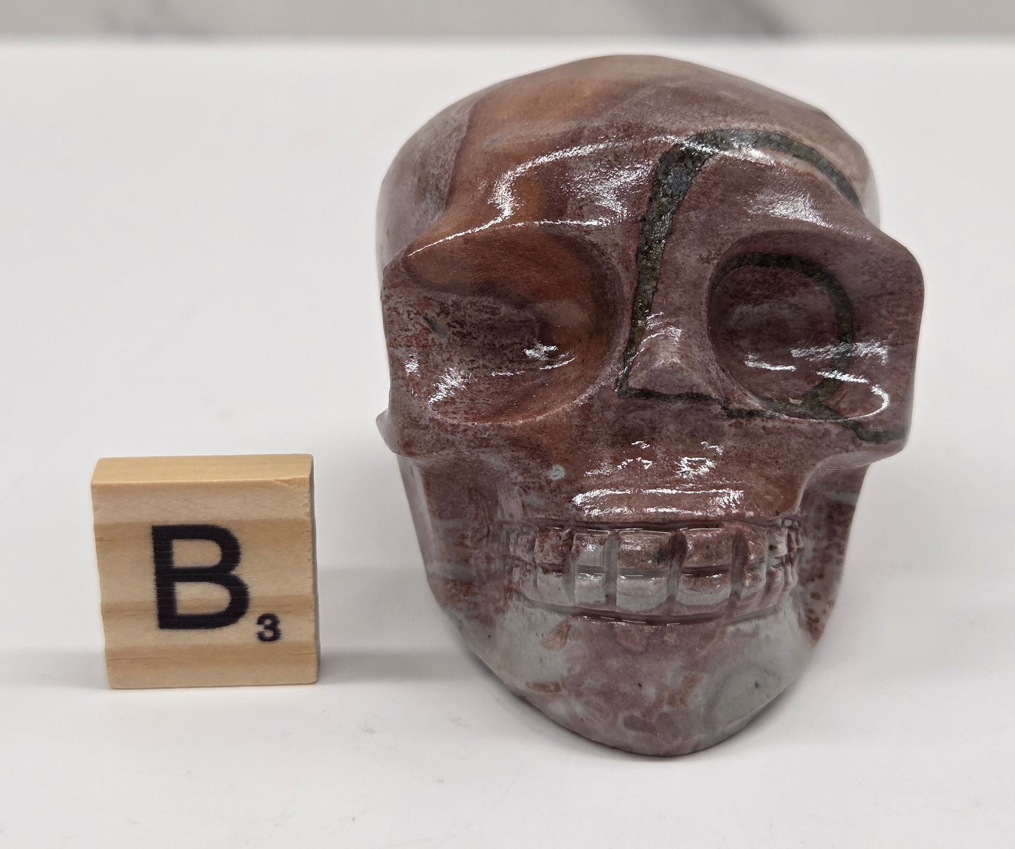 skull carving with pink and grey coloring on a white background