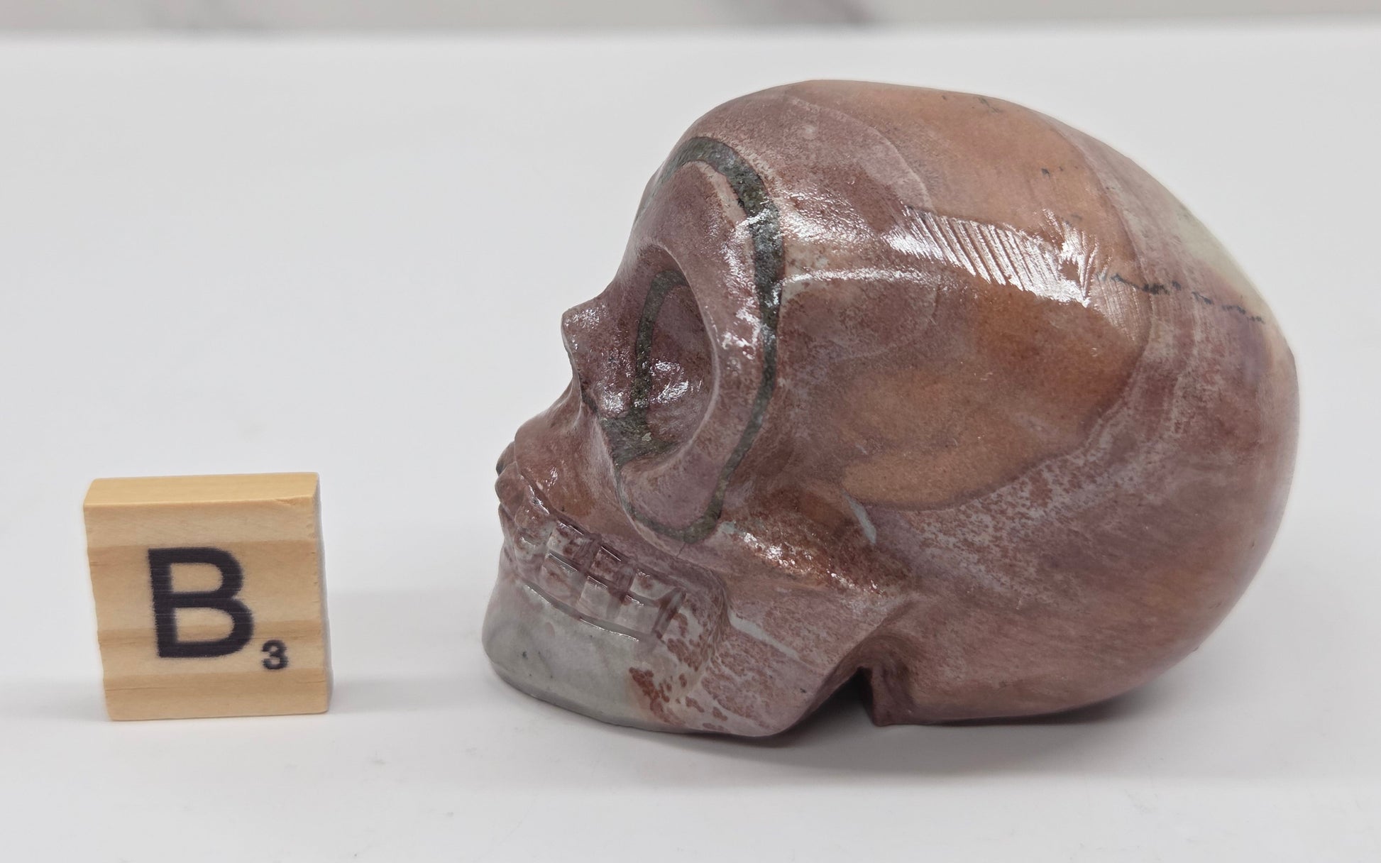 skull carving with pink and grey coloring on a white background