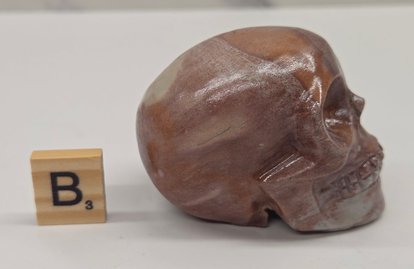 skull carving with pink and grey coloring on a white background