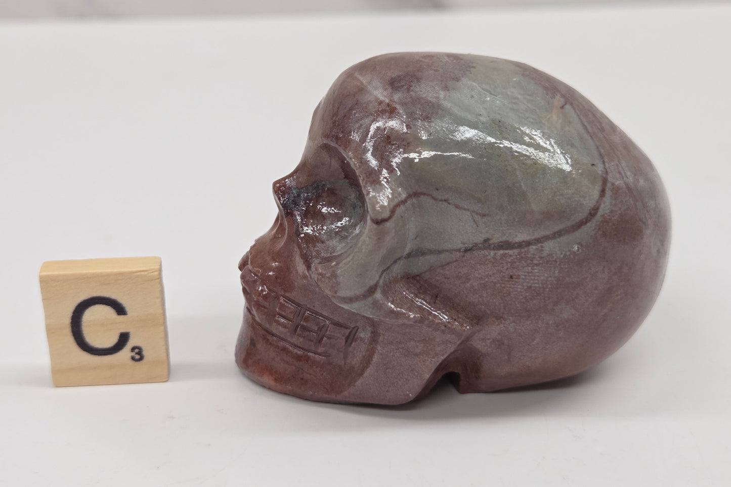 skull carving with pink and grey coloring on a white background