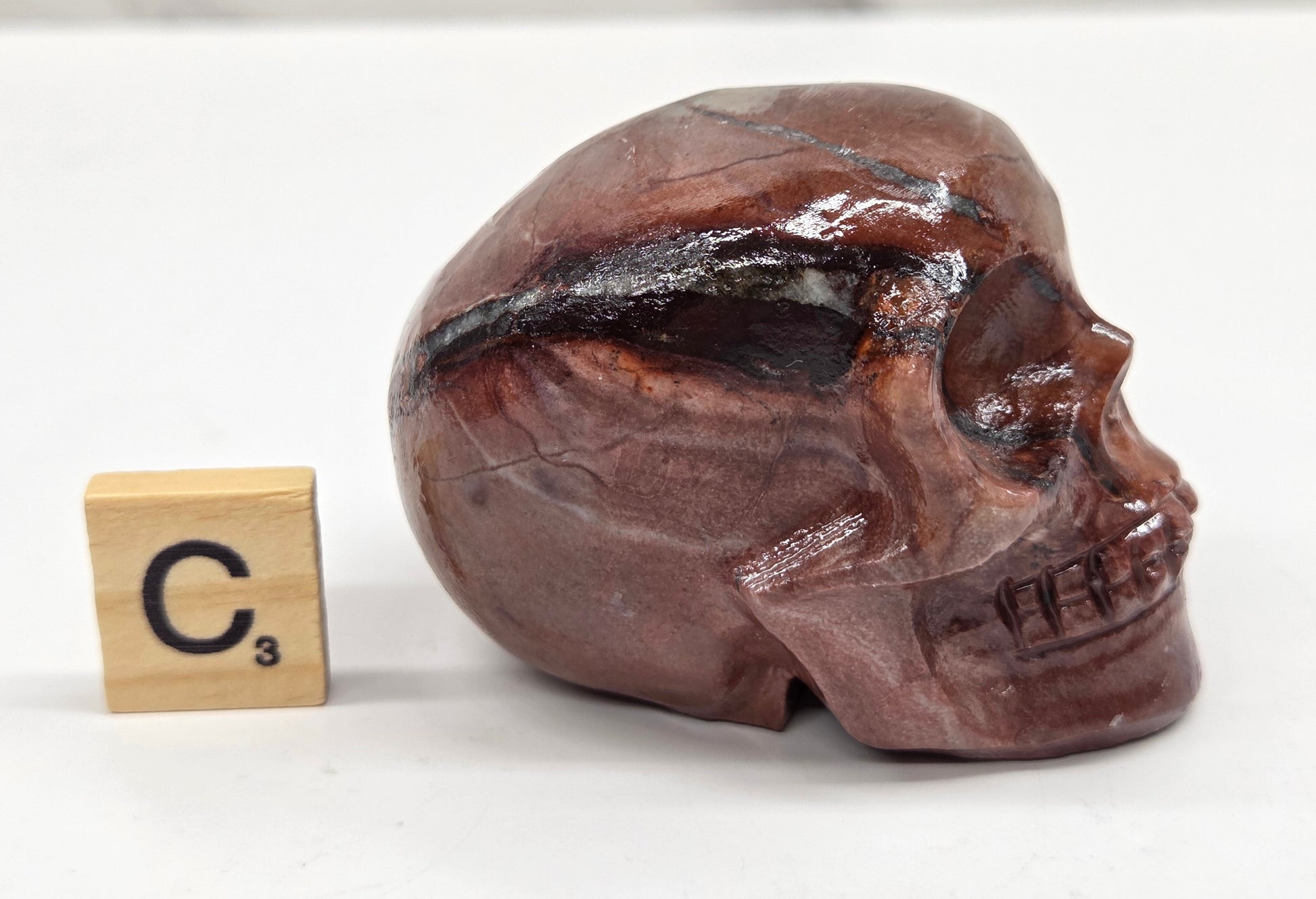 skull carving with pink and grey coloring on a white background