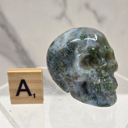 Moss Agate skull carving on a white background