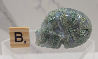 Moss Agate skull carving on a white background