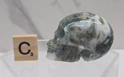 Moss Agate skull carving on a white background