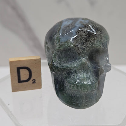 Moss Agate skull carving on a white background