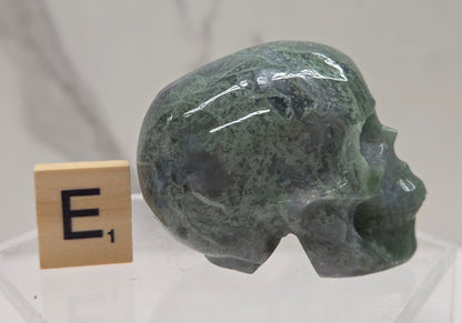 Moss Agate skull carving on a white background