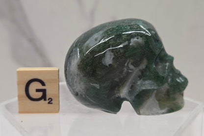 Moss Agate skull carving on a white background