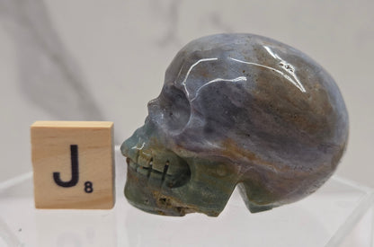 Moss Agate skull carving on a white background