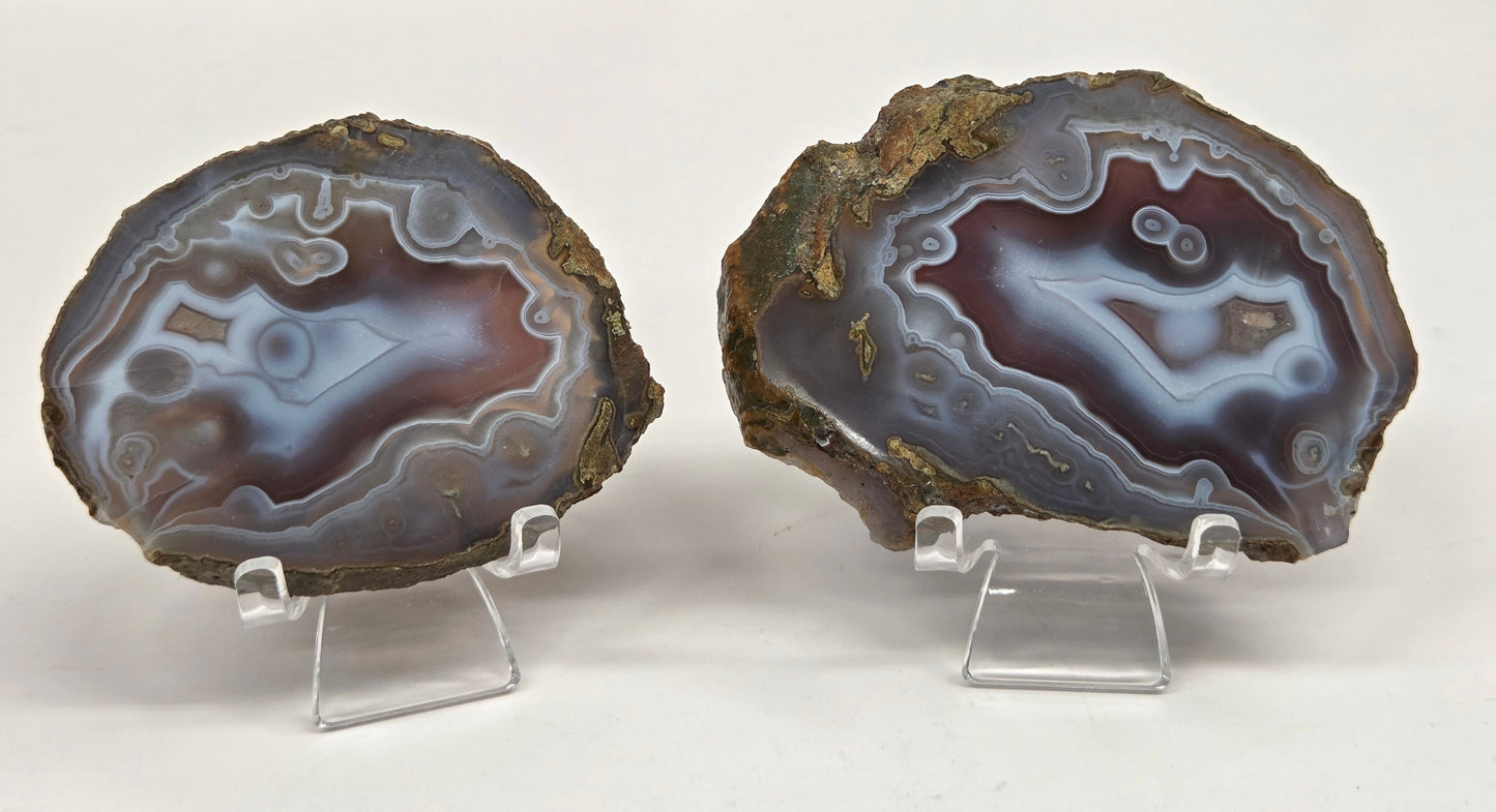 Mineral slab with grey and red coloring and banding on acrylic chairs against a white background