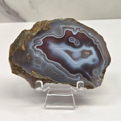 Mineral slab with grey and red coloring and banding on acrylic chairs against a white background