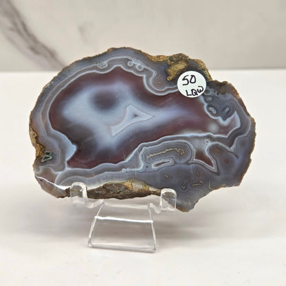 Mineral slab with grey and red coloring and banding on acrylic chairs against a white background