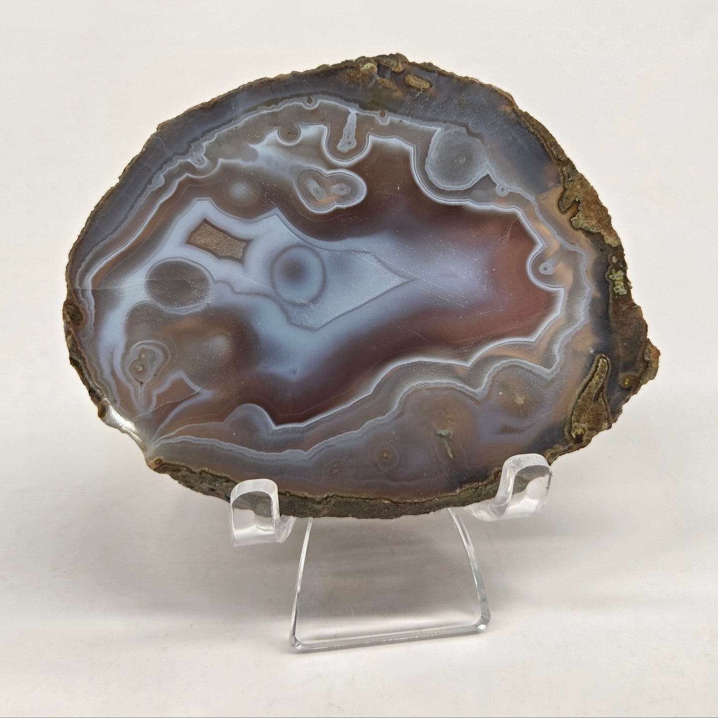 Mineral slab with grey and red coloring and banding on acrylic chairs against a white background
