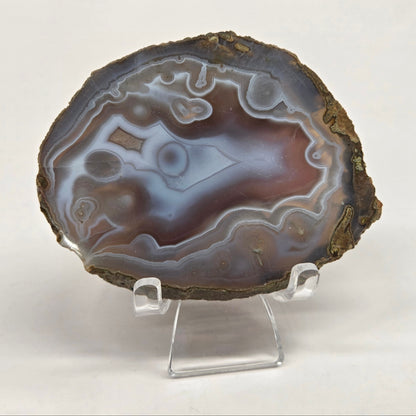 Mineral slab with grey and red coloring and banding on acrylic chairs against a white background