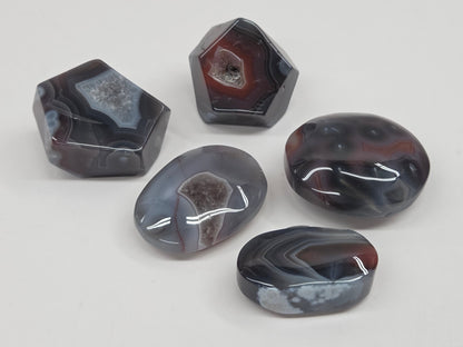 Agate free forms with grey and red coloring and banding against a white background
