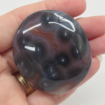 Agate free form with grey and red coloring and banding against a white background