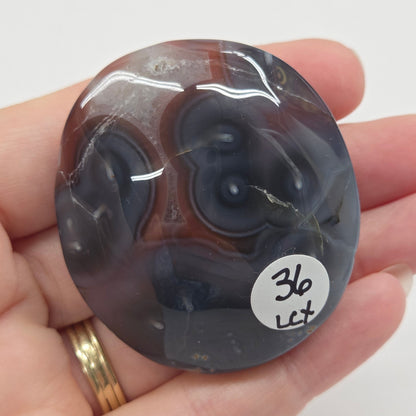 Agate free form with grey and red coloring and banding against a white background