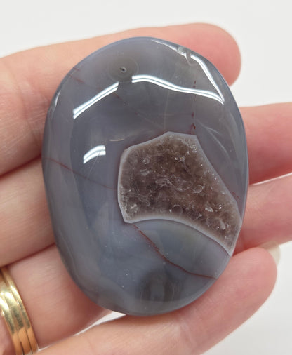 Agate free form with grey and red coloring and banding against a white background