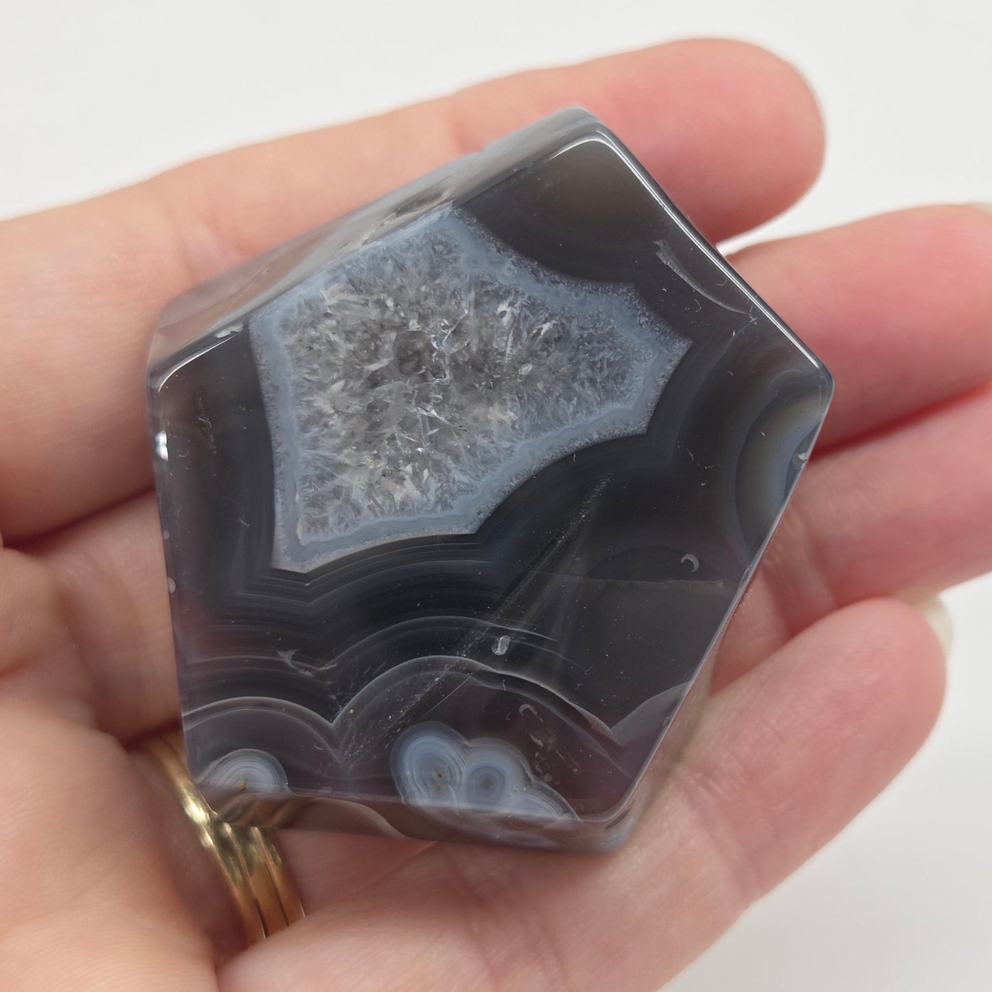 Agate free form with grey and red coloring and banding against a white background