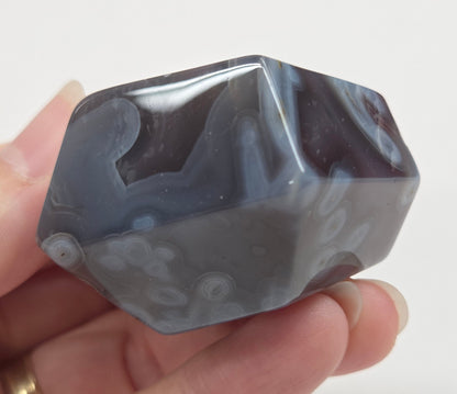 Agate free form with grey and red coloring and banding against a white background