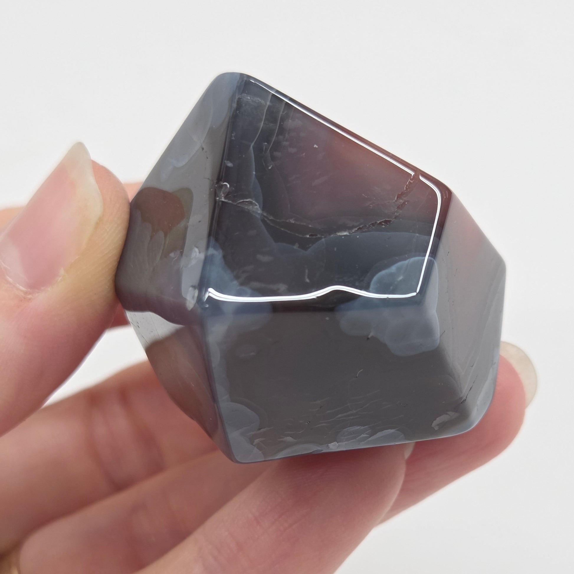 Agate free form with grey and red coloring and banding against a white background