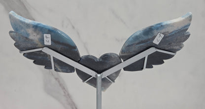 wing and heart carving with black, blue and white coloring on a silver stand against a white background