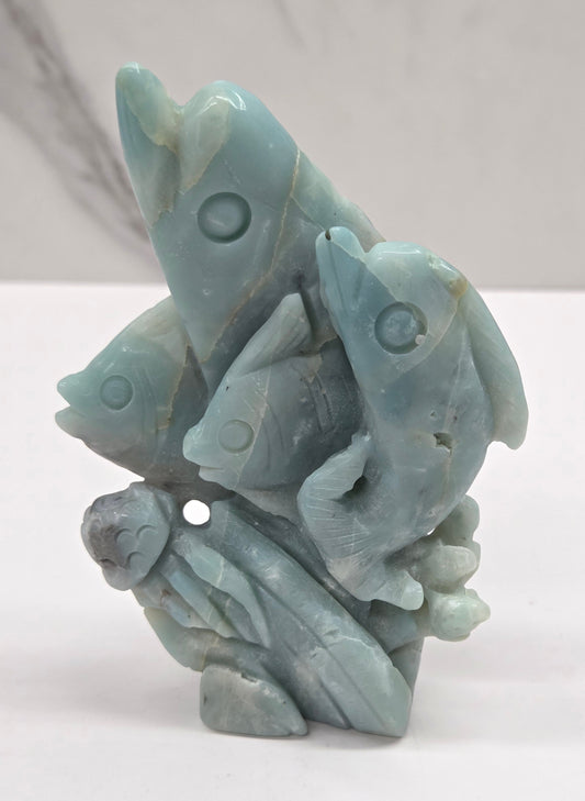 Caribbean Calcite carving of dolphins, fish and jellyfish on a white background