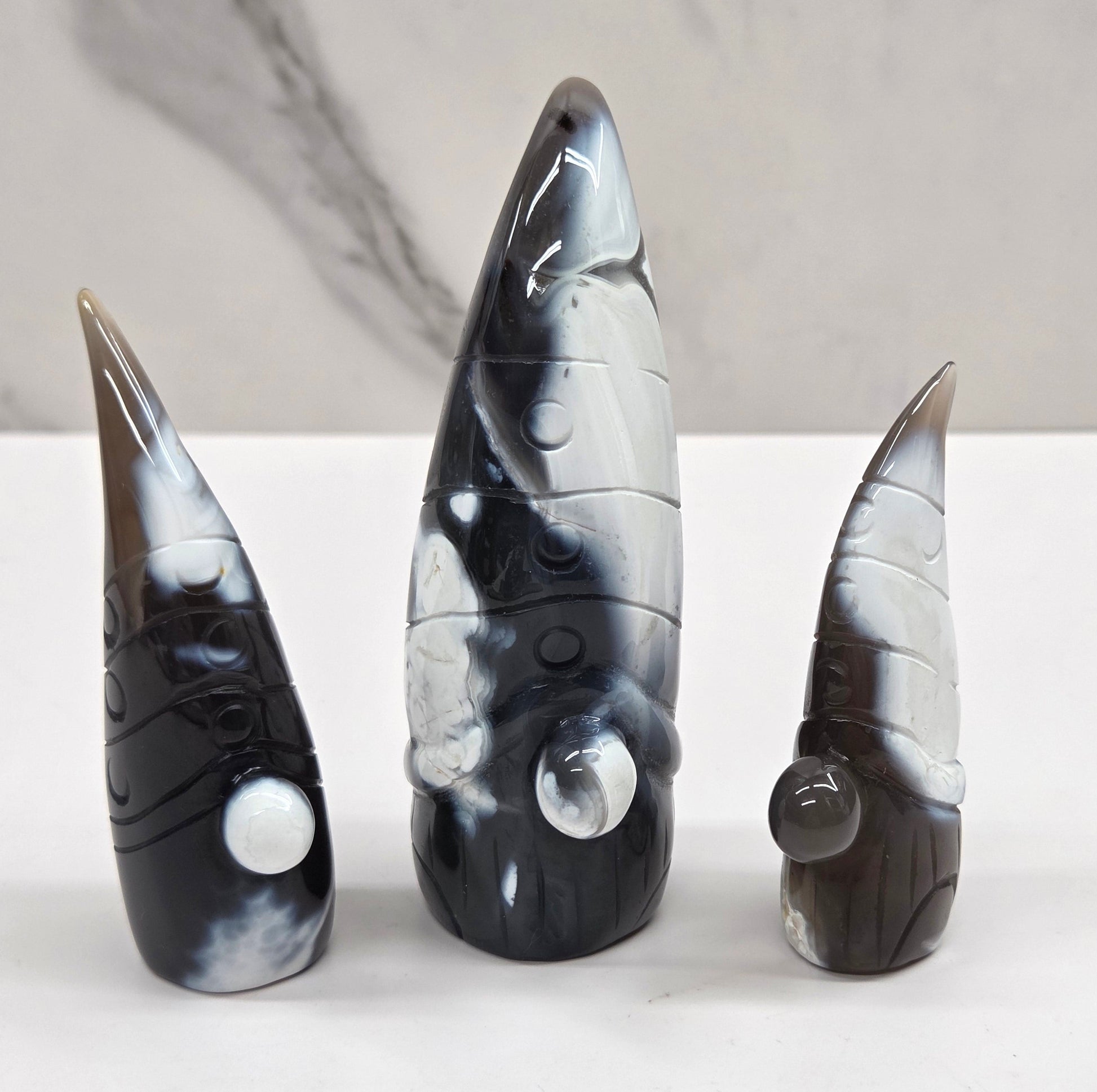 Black and white agate gnome shaped carvings on a white background