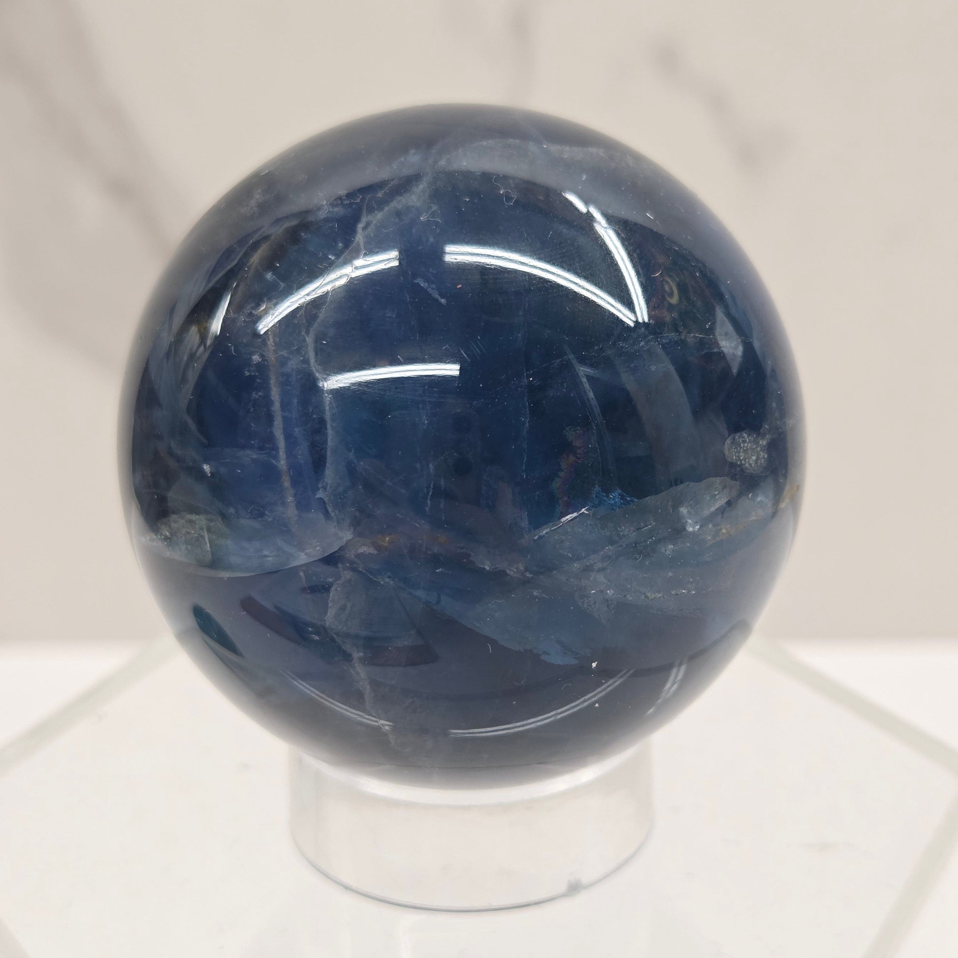 Blue Fluorite sphere on an acrylic stand against a white background