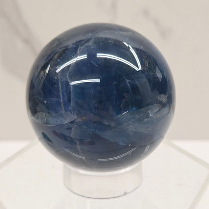 Blue Fluorite sphere on an acrylic stand against a white background