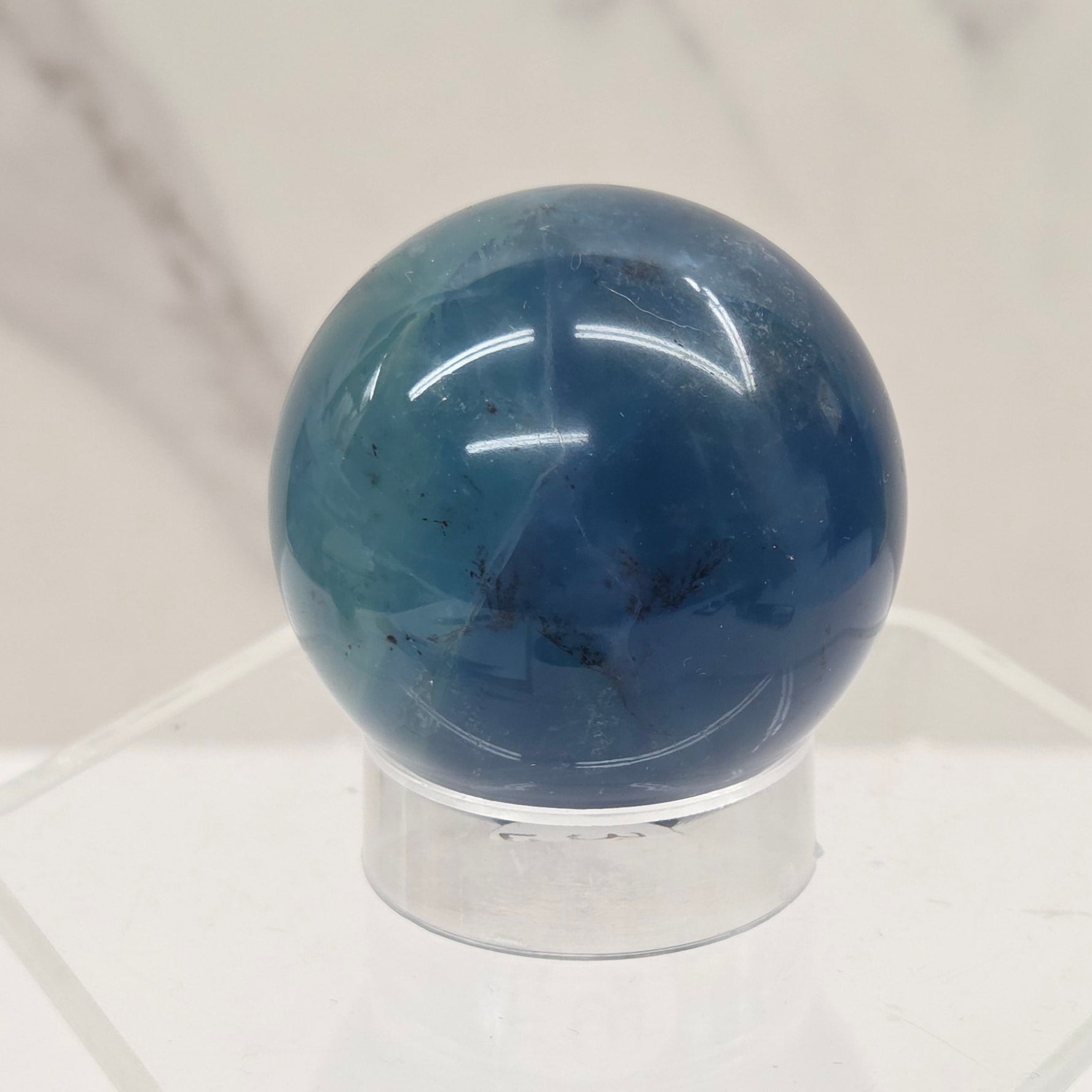 Blue Fluorite sphere on an acrylic stand against a white background