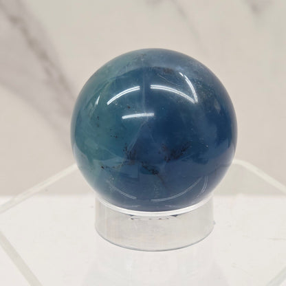 Blue Fluorite sphere on an acrylic stand against a white background