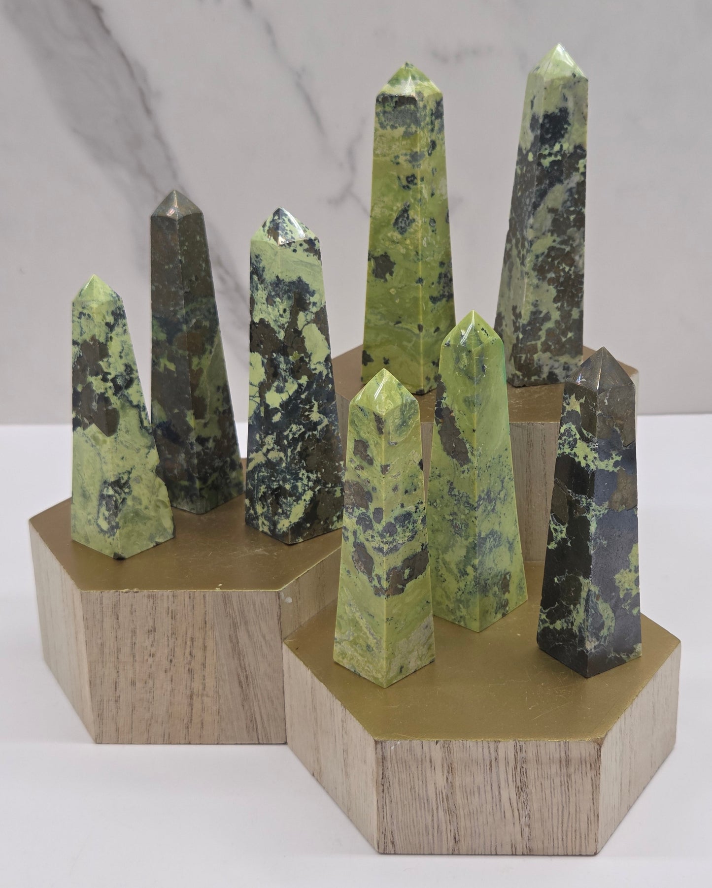 Collection of green and brown towers on a wooden stand against a white background