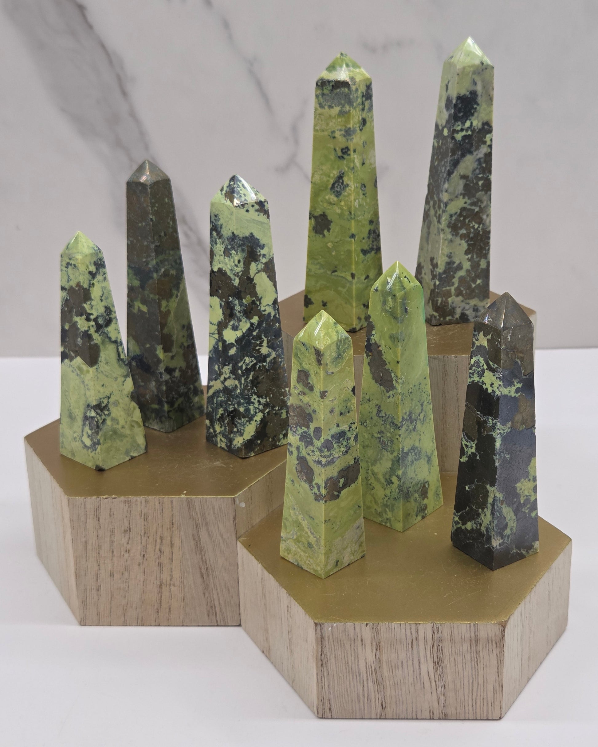 Collection of green and brown towers on a wooden stand against a white background