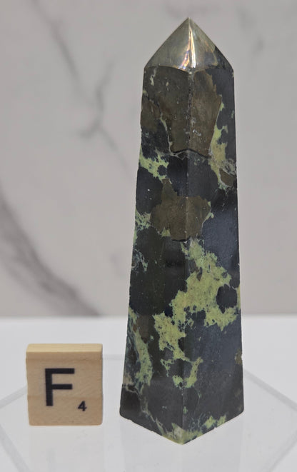 Green and brown crystal tower on an acrylic stand against a white background