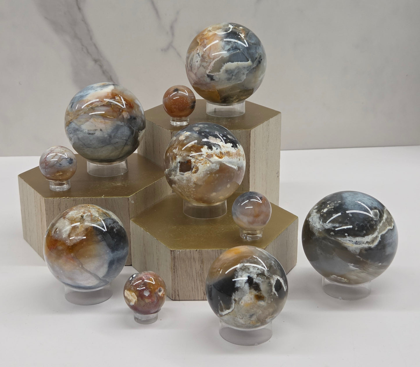 Petrified wood spheres with multiple colors on a wood stand against a white background