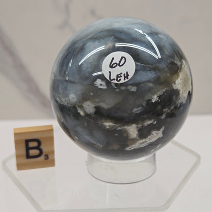 Petrified wood sphere with multiple colors on an acrylic stand against a white background