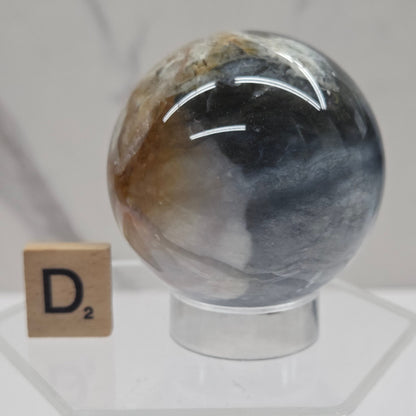 Petrified wood sphere with multiple colors on an acrylic stand against a white background