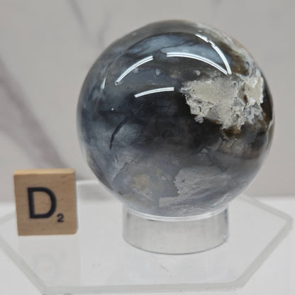 Petrified wood sphere with multiple colors on an acrylic stand against a white background