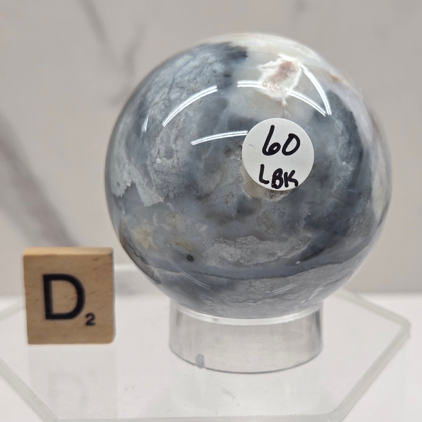 Petrified wood sphere with multiple colors on an acrylic stand against a white background