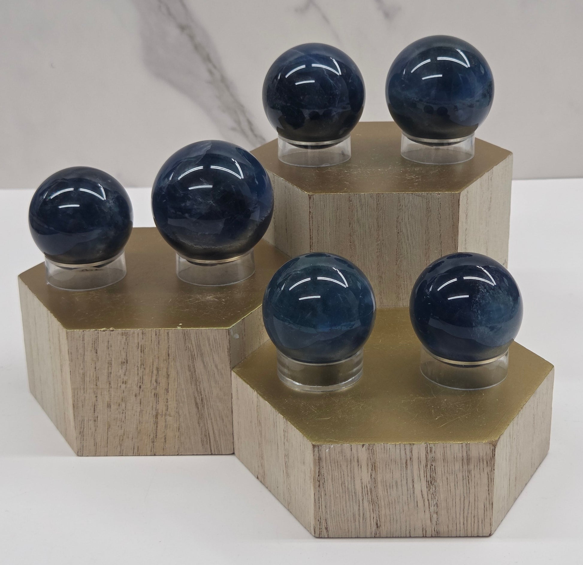 A collection of blue fluorite spheres on a wooden stand against a white background