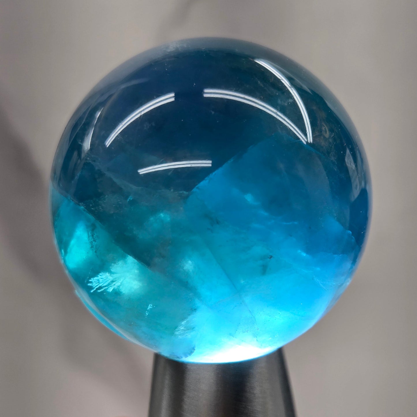 Blue fluorite sphere with a backlight against a white background