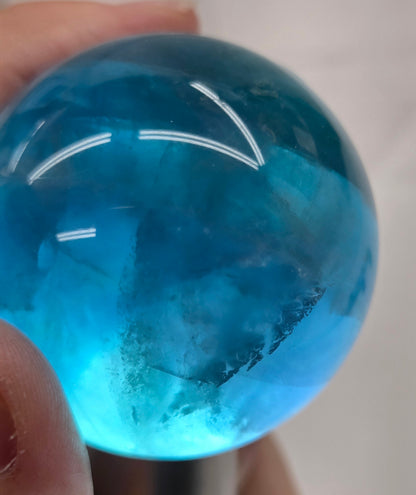 Blue fluorite sphere with a backlight against a white background