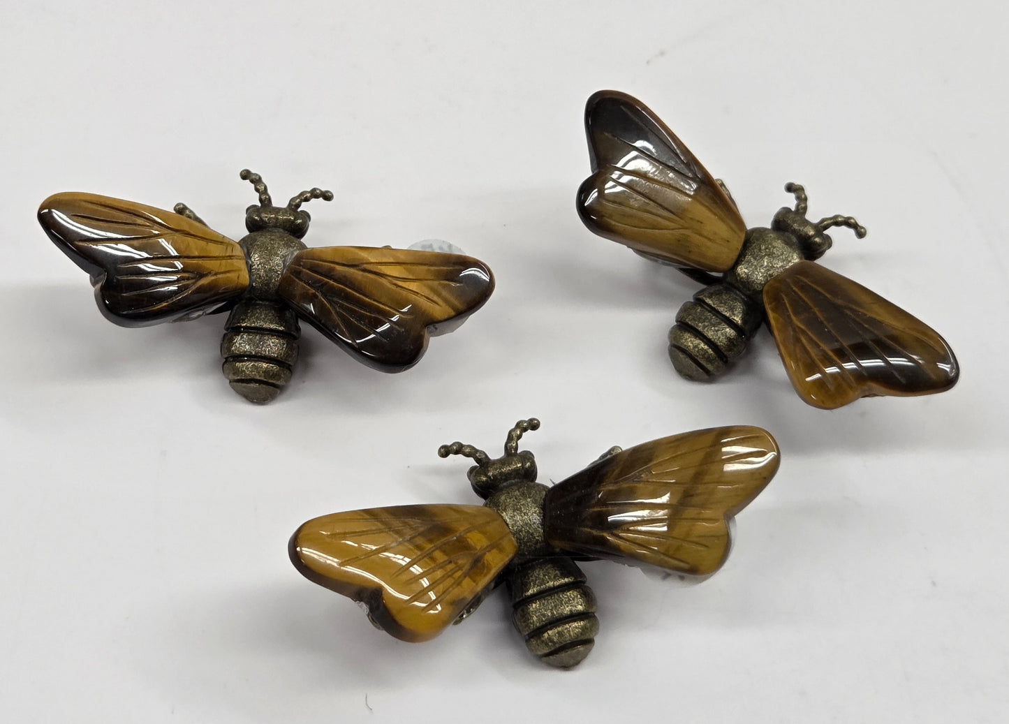 Collection of brass bees with tigers eye wings on a white background