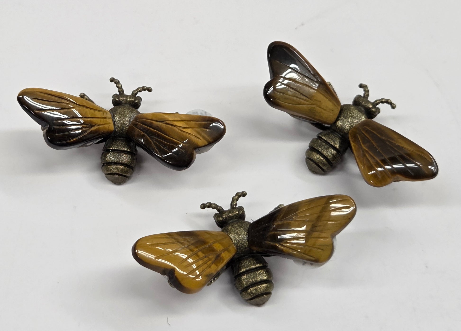 Collection of brass bees with tigers eye wings on a white background