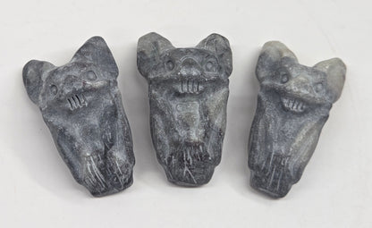 Grey crystal bat carvings on a white background
