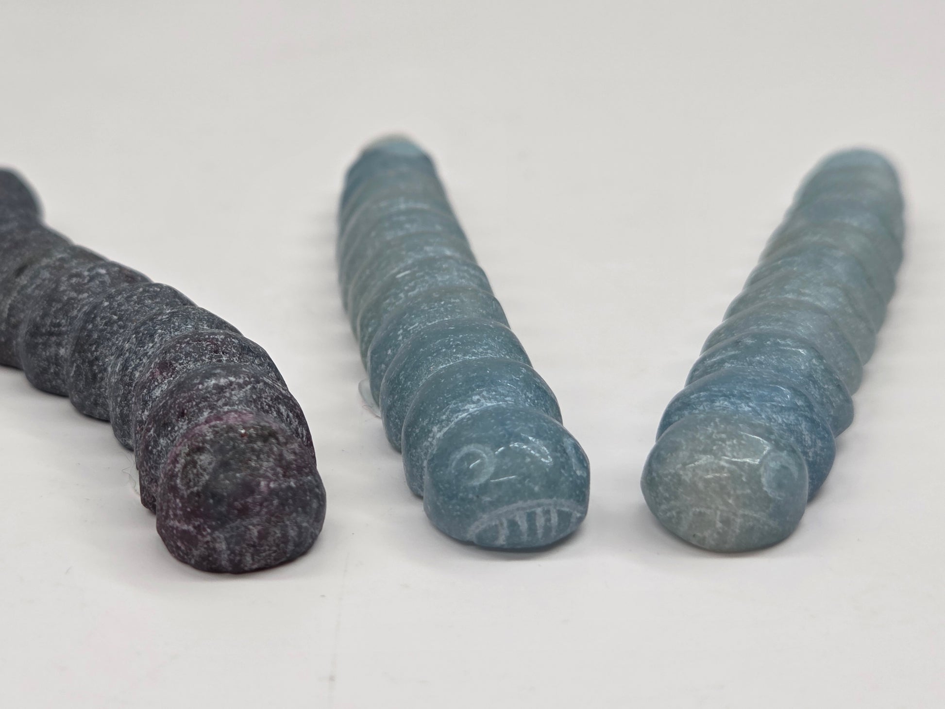 Close-up of crystal worm-like sculptures with face carvings on a white background