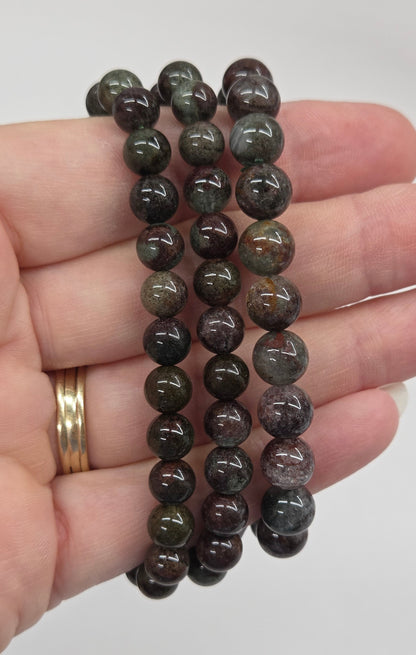 Hand holding a beaded bracelet against a plain background
