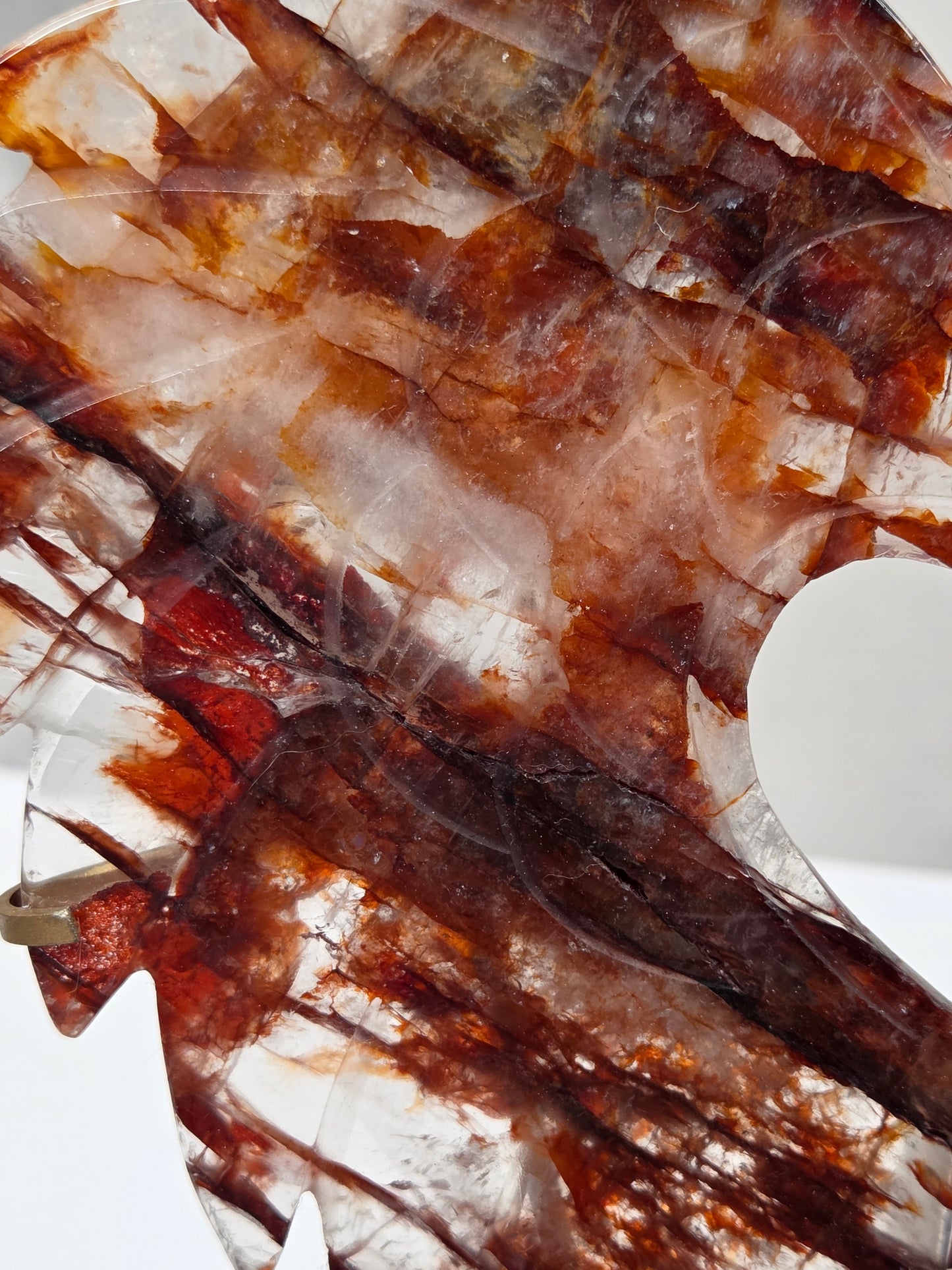 A close-up of a translucent decorative object with layered brown, amber, and white crystalline or stone-like patterns, photographed against a white background.